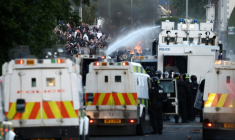 PLa police utilise des canons à eau pour bloquer la route aux manifestants à Glegormley, au nord de Belfast, le 10 juin 2026 en Irlande du Nord ( AFP / Henry NICHOLLS )