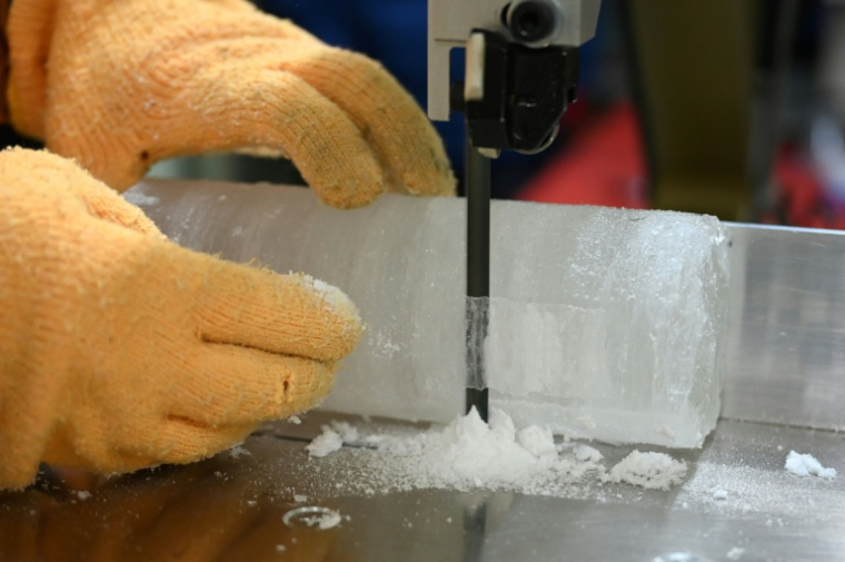 Le professeur Yoshinori Iizuka coupe une tranche d'un échantillon de carotte de glace, à l'Institut des sciences cryogéniques de l'université d'Hokkaido, à Sapporo, au Japon, le 9 décembre 2025 ( AFP / GREG BAKER )