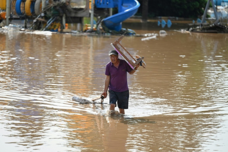 Un habitant portant une table traverse une zone inondée après de fortes pluies dans le village de Taishitun, dans le district de Miyun, à la périphérie de Pékin, le 28 juillet 2025 ( AFP / Jade GAO )