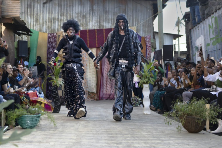 Le styliste Morgan Azedy présente avec un mannequin les tenues qu'il a créées à partir de tissus et de vêtements mis au rebut, lors du défilé de mode Gikomba Runway Edition à Nairobi, le 10 octobre 2025 au Kenya ( AFP / Tony KARUMBA )