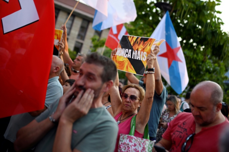 Une femme brandit une affiche clamant "Nunca Mais" (Plus Jamais) durant une manifestation dénonçant la gestion des feux de forêt, à Verin, dans le nord-ouest de l'Espagne, le 21 août 2025 ( AFP / Miguel RIOPA )