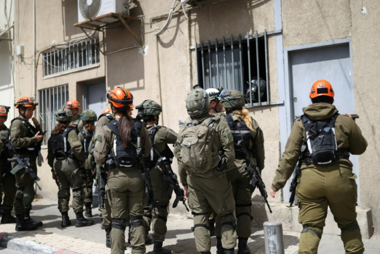Des membres des forces de sécurité israéliennes et des secouristes sur le site d'une frappe de projectile dans le sud de Tel-Aviv, le 26 mars 2026 ( AFP / Ilia YEFIMOVICH )