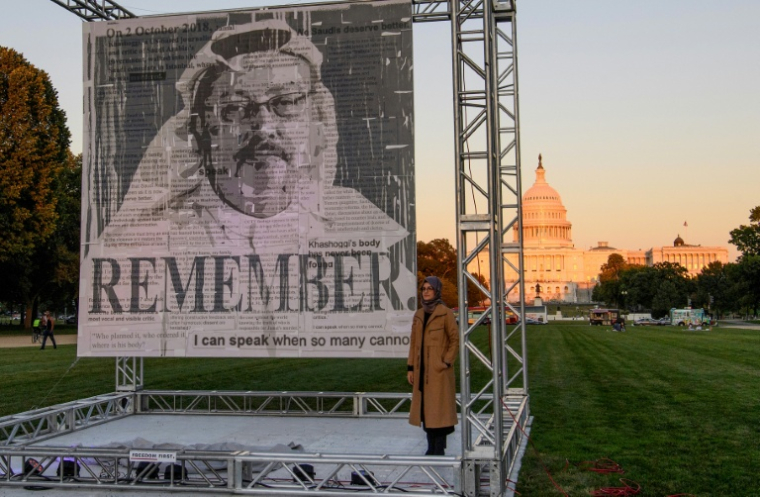 L'écrivaine turque Hatice Cengiz (d), fiancée du journaliste et dissident saoudien Jamal Khashoggi, devant un portrait du journaliste Jamal Khashoggi assassiné, après son dévoilement sur le National Mall à Washington, le 1er octobre 2021 ( AFP / Nicholas Kamm )