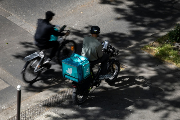 Des livreurs Deliveroo à vélo dans une rue de Paris, le 28 avril 2026 ( AFP / Joel Saget )
