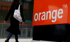 Une femme passe devant le logo de l'opérateur télécom français Orange au siège de l'entreprise à Issy-les-Moulineaux près de Paris