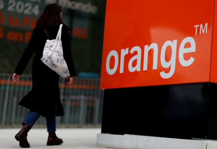 Une femme passe devant le logo de l'opérateur télécom français Orange au siège de l'entreprise à Issy-les-Moulineaux près de Paris