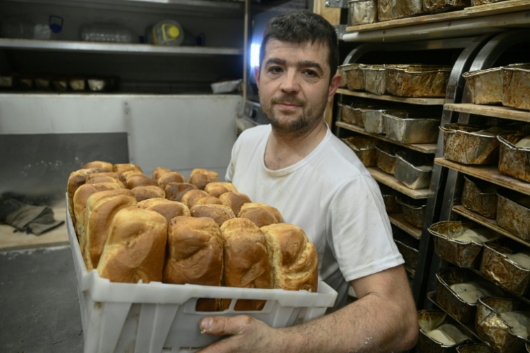 Le boulanger bénévole français Loïc Nervi tient un panier de pain fraîchement cuit dans sa boulangerie mobile afin de le distribuer aux résidents d'un logement temporaire pour les personnes qui ont perdu leur maison et les personnes déplacées à Borodianka, dans la région de Kiev, le 19 février 2026, dans le contexte de l'invasion russe de l'Ukraine. ( AFP / Genya SAVILOV )