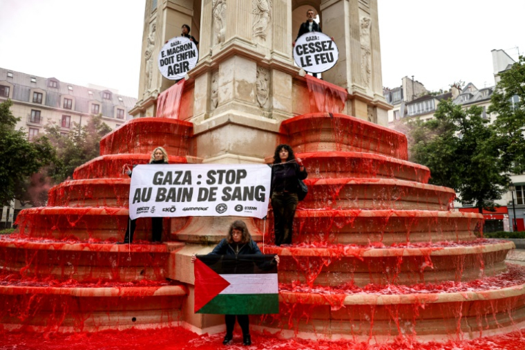 Des militants pro-palestiniens manifestent devant la Fontaine des Innocents dans laquelle des litres de colorant alimentaire rouge ont été déversés, le 28 mai 2025 à Paris ( AFP / Leo VIGNAL )
