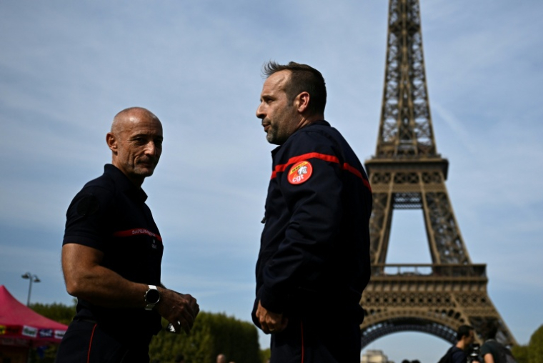 Des pompiers mobilisés contre le manque de moyens à leurs dispositions, sur le campement installé au pied de la tour Eiffel à Paris, le 27 septembre 2026 ( AFP / JULIEN DE ROSA )