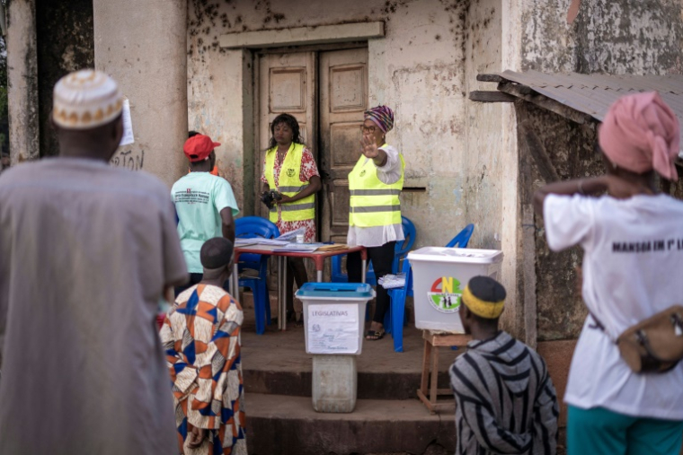 Une responsable de la Commission électorale nationale (CNE) invite les électeurs à reculer au bureau de vote 61-1 à Mansoa (Guinée-Bissau) avant l'ouverture du scrutin, lors des élections présidentielle et législatives en Guinée-Bissau, le 23 novembre 2025 ( AFP / Samba BALDE )