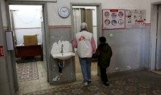 Une membre du personnel de Médecins sans frontières accompagne un jeune garçon dans une clinique de Gaza City le 31 décembre 2025 ( AFP / Omar AL-QATTAA )