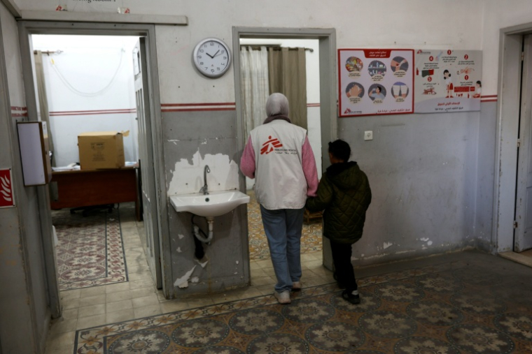 Une membre du personnel de Médecins sans frontières accompagne un jeune garçon dans une clinique de Gaza City le 31 décembre 2025 ( AFP / Omar AL-QATTAA )
