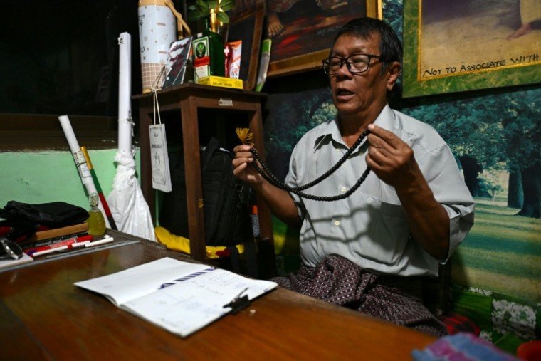 L'astrologue Min Thein Kyaw lors d'une séance de voyance avec un client, le 17 décembre 2025 à Rangoun  ( AFP / Sai Aung MAIN )