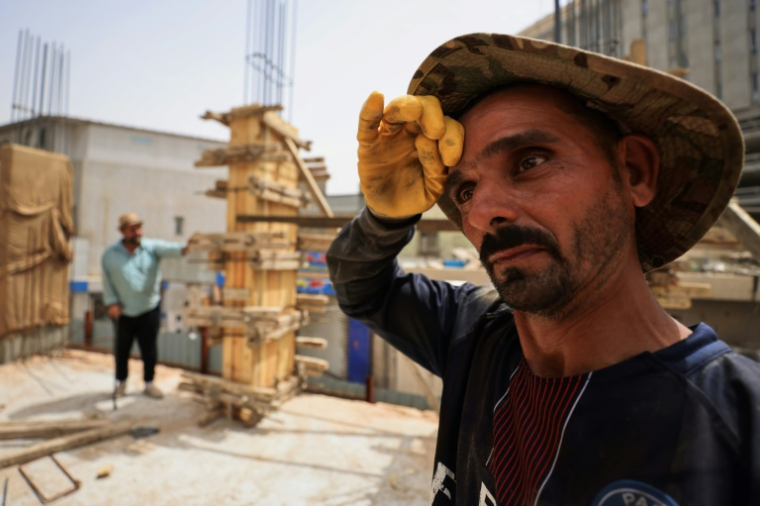 Un ouvrier sur un chantier de construction essuie la sueur de son front alors que les températures augmentent avec l'arrivée de l'été à Bagdad, le 28 mai 2025 en Irak ( AFP / AHMAD AL-RUBAYE )
