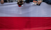 Une femme tient un tract de campagne du maire de Varsovie et candidat à la présidence, Rafal Trzaskowski, alors qu'elle et d'autres partisans de M. Trzaskowski se rassemblent sur le marché principal de Skierniewice, en Pologne, le 16 mai 2025 ( AFP / Wojtek RADWANSKI )