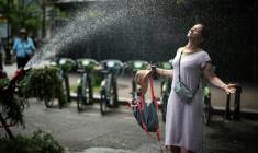 Une femme se rafraîchit devant un tuyau d'arrosage à Paris, le 18 juin 2026 ( AFP / Simon WOHLFAHRT )
