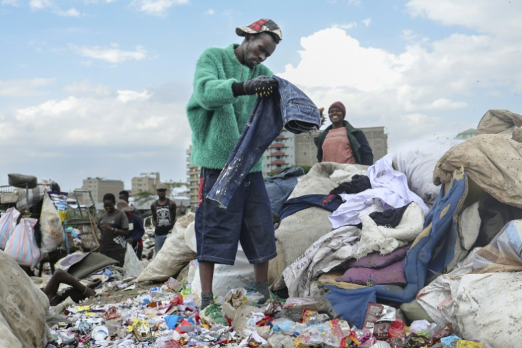 Le créateur de mode Morgan Azedy fouille dans des piles de vêtements mis au rebut dans une décharge à Nairobi, le 6 octobre 2025 au Kenya ( AFP / Tony KARUMBA )