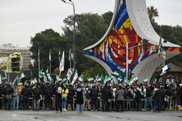 Des habitants brandissent des drapeaux syriens à Damas, pour célébrer le premier anniversaire de la destitution de Bachar al-Assad, le 8 décembre 2025 en Syrie ( AFP / LOUAI BESHARA )