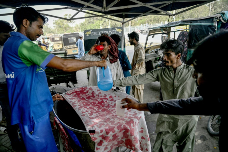 Un bénévole distribue de l'eau froide aux passants en pleine vague de chaleur à Karachi, au Pakistan, le 29 mai 2025 ( AFP / Rizwan TABASSUM )
