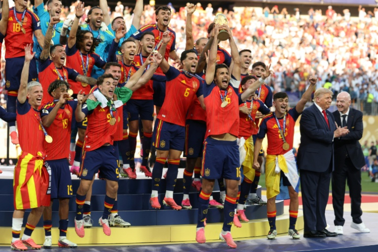 Le milieu de terrain espagnol, Rodri, brandit le trophée de la Coupe du monde aux côtés de ses coéquipiers, encadré par le président américain Donald Trump (2e à droite) et le président de la Fifa Gianni Infantino (à droite), après avoir remporté la finale du Mondial-2026 contre l'Argentine, à East Rutherford, le 19 juillet 2026 ( AFP / Odd ANDERSEN )