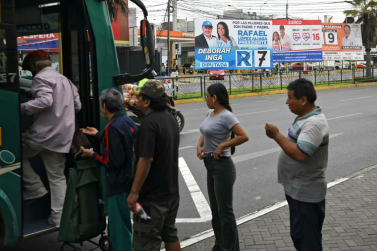 Des personnes montent dans un bus près d'affiches de campagne à Lima, le 11 avril 2026 ( AFP / Luis ROBAYO )