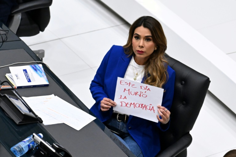 La députée d'opposition Macela Villatoro brandit une pancarte avec a phrase "la démocratie est morte aujourd'hui" pendant l'examen par le Parlement d'une réforme permettant la réélection indéfinie du président, le 31 juillet 2025 ( AFP / Marvin RECINOS )