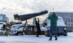 Une femme pose sur fond d'un drone russe Shahed abattu et exposé à Kiev, le 17 février 2026  ( AFP / HENRY NICHOLLS )