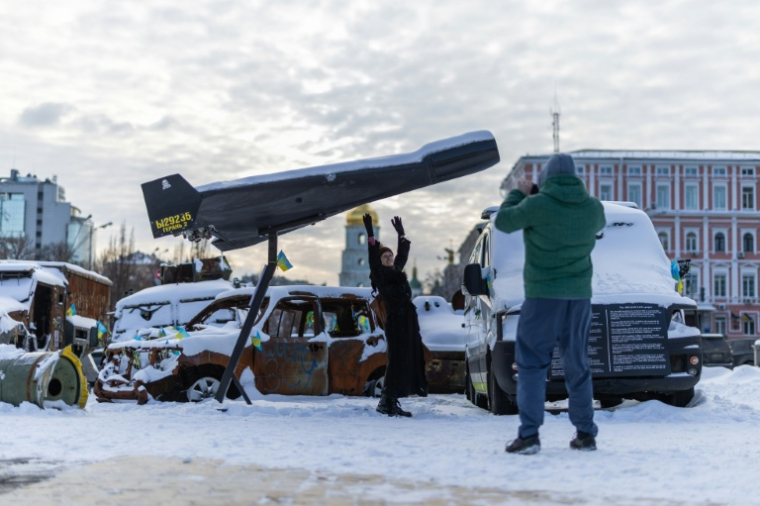 Une femme pose sur fond d'un drone russe Shahed abattu et exposé à Kiev, le 17 février 2026  ( AFP / HENRY NICHOLLS )
