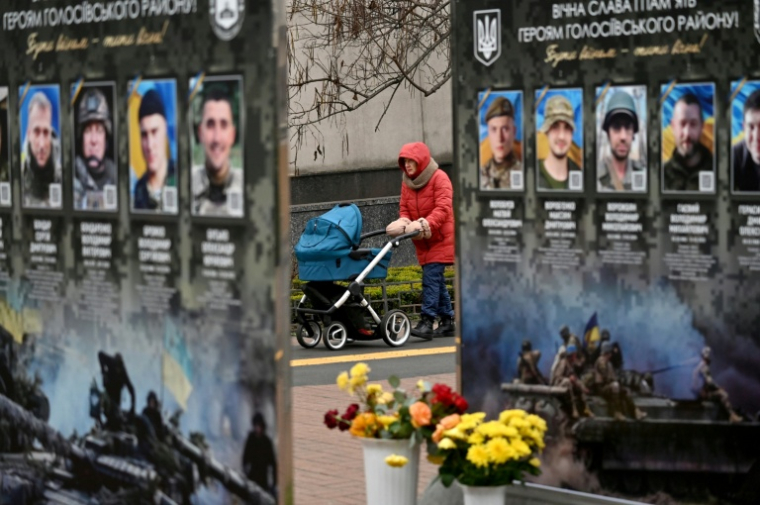 Une femme et son enfant tarversent un site en mémoire aux combattants ukrainiens tombés face aux troupes russes, à Kiev, le 7 décembre 2025 ( AFP / Sergei SUPINSKY )