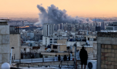 Des personnes sur le toit d'un immeuble observent un panache de fumée après une frappe sur  Téhéran, le 3 mars 2026 en Iran ( AFP / ATTA KENARE )