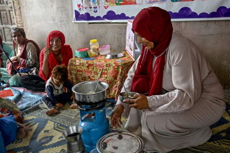 Une travailleuse sociale (d) montre à des mères comment préparer des repas nutritifs pour leurs enfants lors d'un programme de nutrition de l'Unicef au village de Fateh Muhammad Soomro, dans la province du Sindh, le 29 juillet 2025 au Pakistan ( AFP / Rizwan TABASSUM )