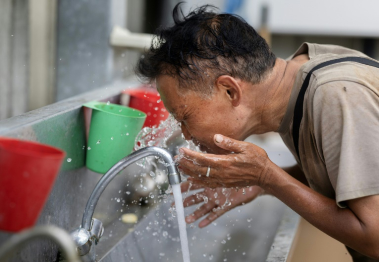 Un employé s'asperge le visage d'eau alors qu'il travaille dans une serre de tomates à Taulé, dans l'ouest de la France, le 25 juin 2026 ( AFP / Fred TANNEAU )