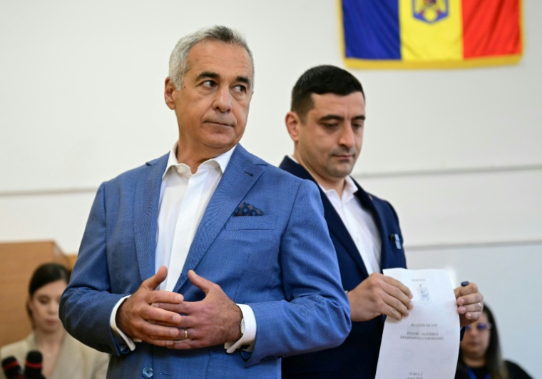 Le chef du parti nationaliste AUR et candidat à la présidentielle roumaine George Simion vote aux côtés de Calin Georgescu, exclu de la course, le 4 mai 2025 à Bucarest ( AFP / Daniel MIHAILESCU )