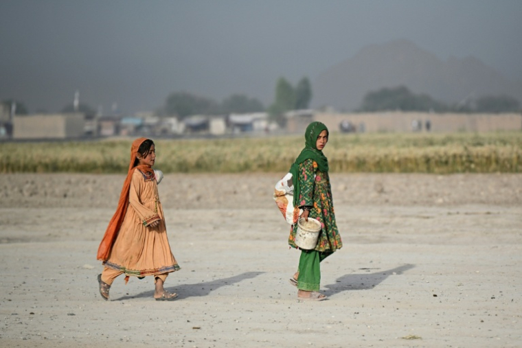 Des jeunes filles nomades afghanes de la tribu des Kochi traversent un village désertique du district de Dand, dans la province de Kandahar, en Afghanistan, le 25 août 2026 ( AFP / Sanaullah SEIAM )