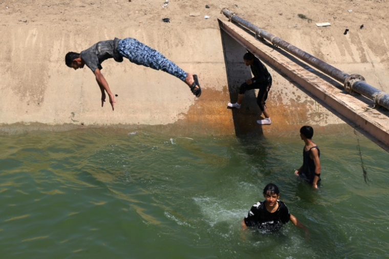 Des jeunes tentent de se rafraîchir en plongeant dans l'eau, à Diwaniyah, dans le sud de l'Irak, le 10 août 2025 ( AFP / AHMAD AL-RUBAYE )