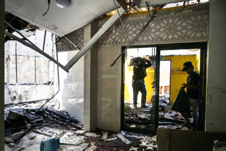 Des policiers nettoient les dégâts le 1er septembre 2025 après l'incendie de leur poste de police lors de manifestations à Surabaya ( AFP / Juni KRISWANTO )
