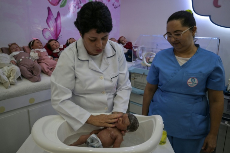 La commerçante Alana Generoso (g) donne le bain à un "bébé reborn" dans sa boutique Maternité Alana Babys à Campinas, dans l'État de Sao Paulo, au Brésil, le 16 mai 2025 ( AFP / NELSON ALMEIDA )