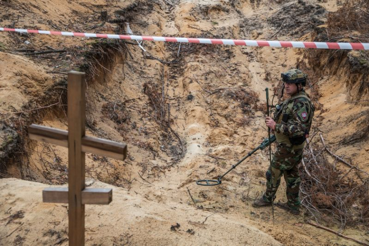 Un militaire ukrainien inspecte un charnier sur le site d'un cimetière improvisé de civils et de soldats ukrainiens dans la ville d'Izioum