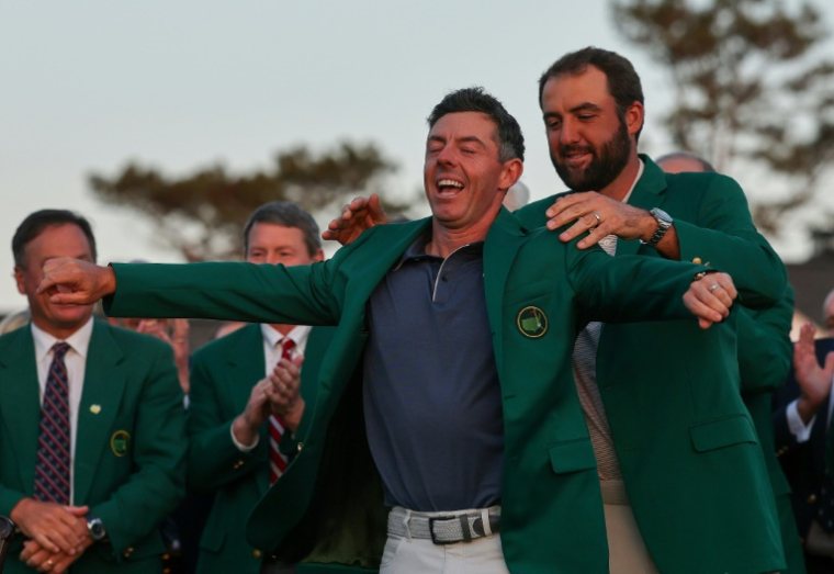 Le Nord-irlandais Rory McIlroy enfile la fameuse veste verte dévolue au vainqueur du Masters de golf d'Augusta, aux Etats-Unis, que lui remet le précédent tenant du titre Scottie Scheffler, le 13 avril 2025 ( GETTY IMAGES NORTH AMERICA / Michael Reaves )