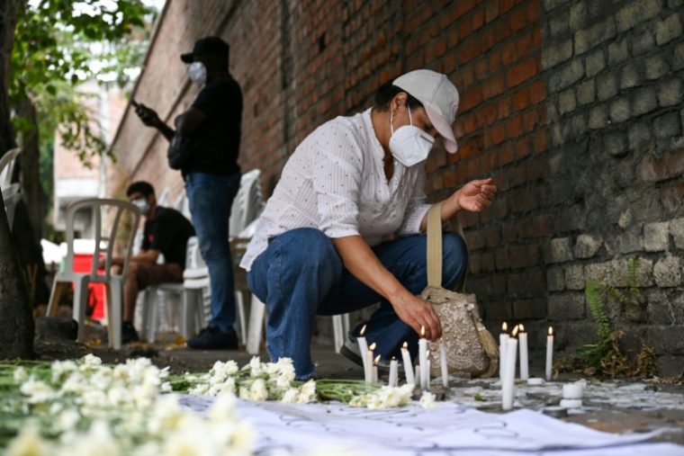 Une bénévole allume un cierge dans un mémorial improvisé dédié aux victimes du séisme, près de la morgue de Palmira, en Colombie, le 14 août 2026 ( AFP / Raul ARBOLEDA )