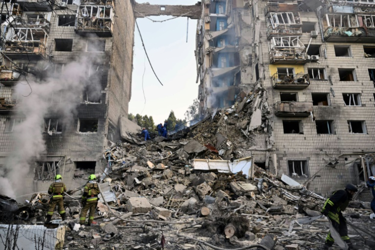 Des sauveteurs ukrainiens dans les décombres d'un immeuble résidentiel gravement endommagé par une frappe de missiles russes, le 17 juin 2025 à Kiev ( AFP / Genya SAVILOV )
