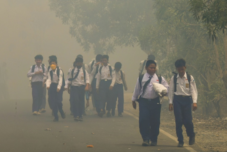 Des écoliers sur une route noyée dans une brume épaisse due aux incendies de forêt et de terres à Banjarbaru ans le Kalimantan du Sud, le 20 octobre 2026 en Indonésie ( AFP / MUDA SAGALA )