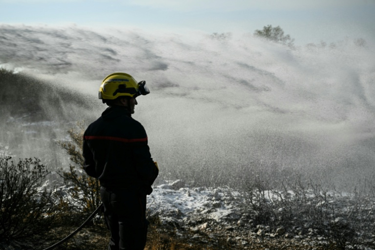 Les pompiers éteignent des cendres chaudes à côté d'Albas, dans le massif des Corbières, le 9 août ( AFP / Bertrand GUAY )