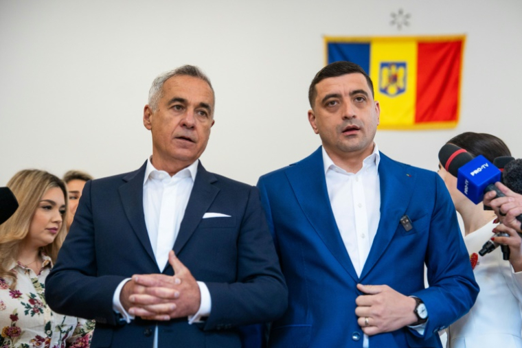 L'ex candidat d'extrême droite à la présidentielle roumaine Calin Georgescu et son successeur George Simion, le 18 mai 2025 dans un bureau de vote de Mogosoaia ( AFP / Mihai Barbu )