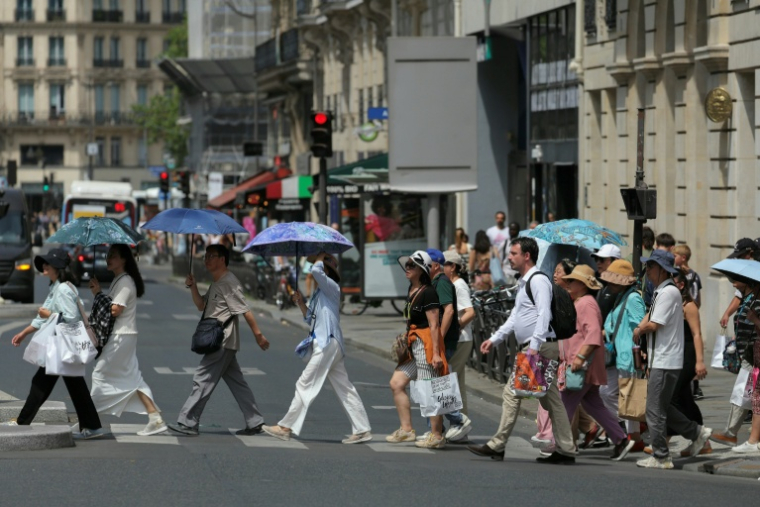 Des touristes se protègent du soleil sous des parapluies à Paris le 23 juin 2026 ( AFP / Thomas SAMSON )