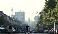 Les véhicules circulent en cette heure de pointe matinale, tandis que la brume du lever du soleil illumine l'horizon de Berlin