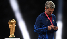 Le joueur Antoine Griezmann regarde sa médaille d'argent en passant devant le trophée de la Coupe du monde à Doha, au Qatar, le 18 décembre. ( AFP / KIRILL KUDRYAVTSEV )
