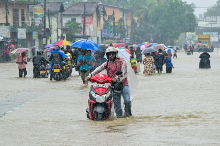 Des habitants pataugent dans une route inondée après de fortes pluies à Kaduwela, en périphérie de Colombo, le 28 novembre 2025 ( AFP / Ishara S. KODIKARA )