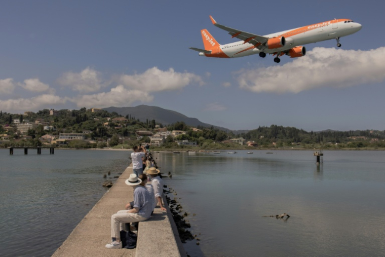 Des touristes regardent un avion de la compagnie low-cost britannique EasyJet qui s'apprête à atterrir sur l'aéroport de l'île de Corfou, en Grèce, le 17 juin 2026 ( AFP / Roman PILIPEY )