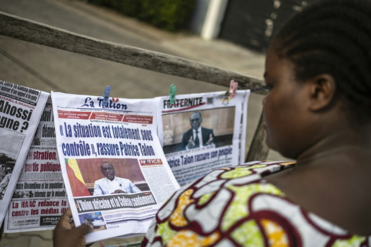 Une habitante regarde les journaux sur un étal dans une rue de Cotonou après une tentative déjouée de coup d'Etat au Bénin, le 8 décembre 2025 ( AFP / OLYMPIA DE MAISMONT )